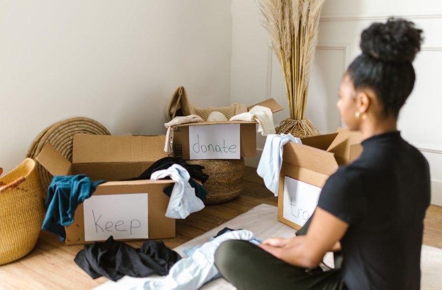 Cardboard boxes labeled "Keep" and "Donate," scattered clothes, wicker basket, home decluttering, sorting belongings, organizing wardrobe, minimalist lifestyle