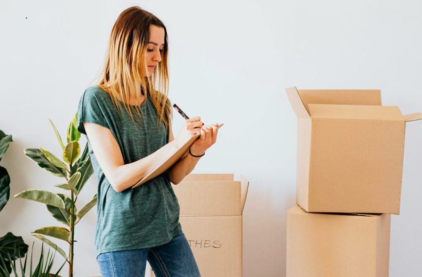 Woman writing list and organizing items in boxes while decluttering