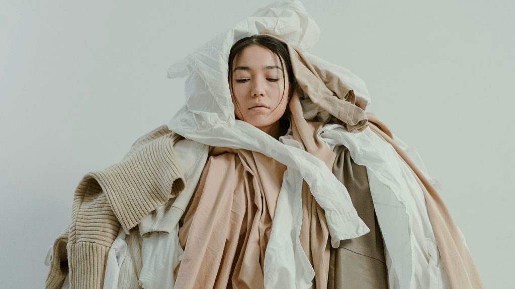 Overwhelmed woman in pile of clothes