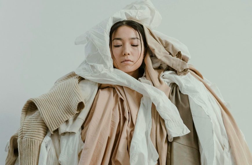 Overwhelmed woman in pile of clothes