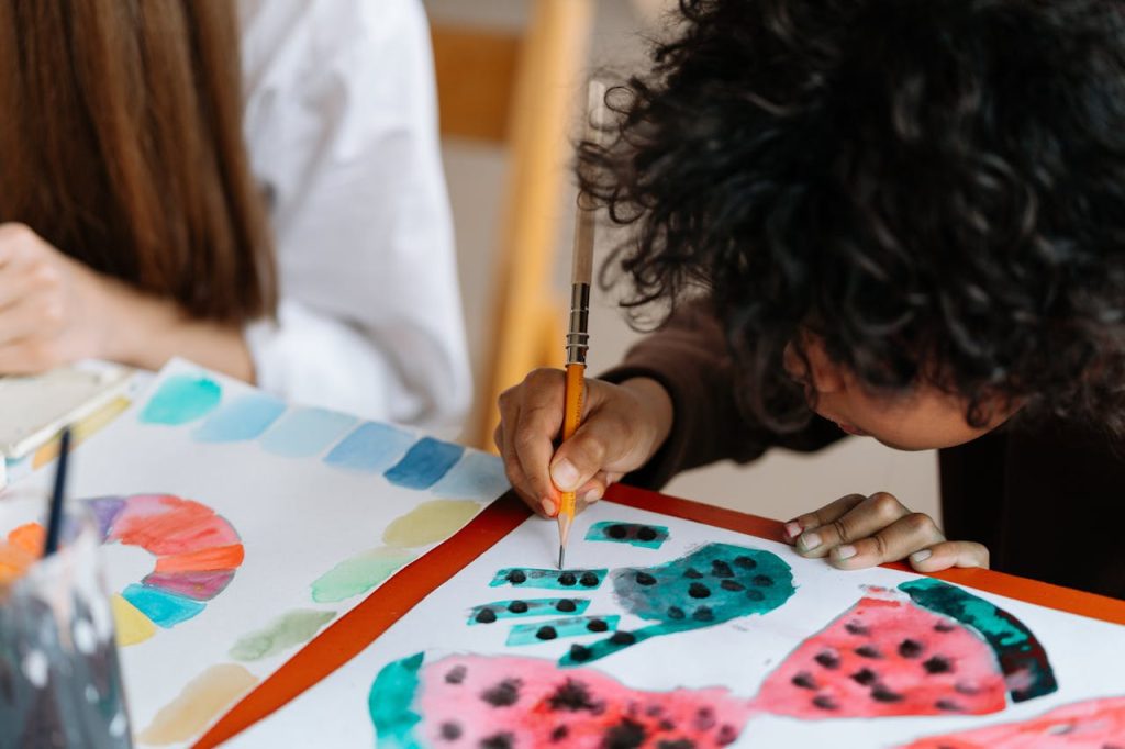 Child painting colorful artwork, using a pencil for details, handprint designs on paper, creative classroom activity, vibrant watercolor patterns, engaging in arts and crafts