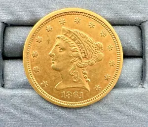 Gold coin from 1861, Lady Liberty design, thirteen stars around the edge, fine details visible, placed on a gray cushioned surface, collectible numismatic item, historical currency
