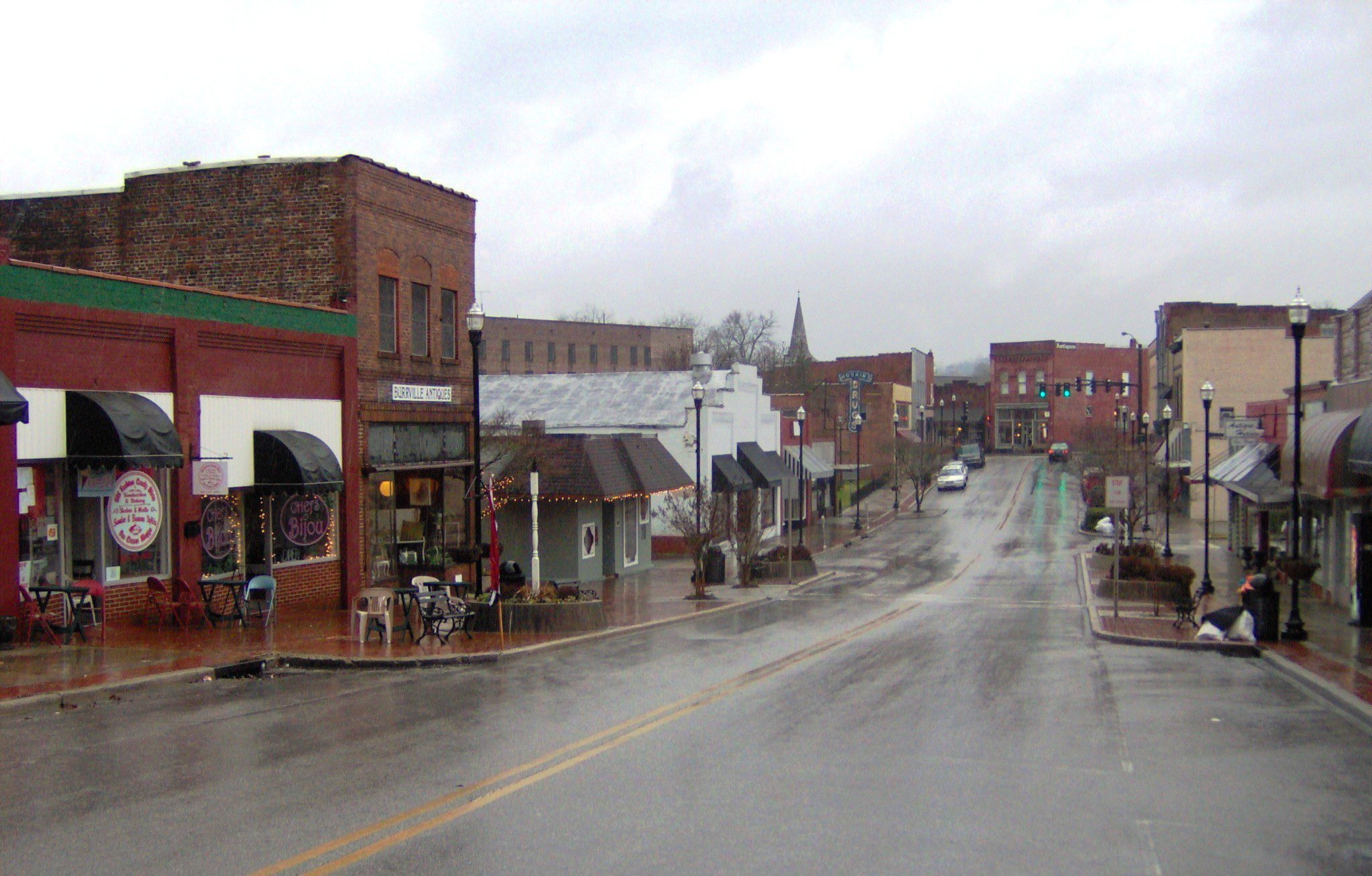 Empty small town street, wet pavement from rain, old brick buildings, overcast sky, quiet atmosphere