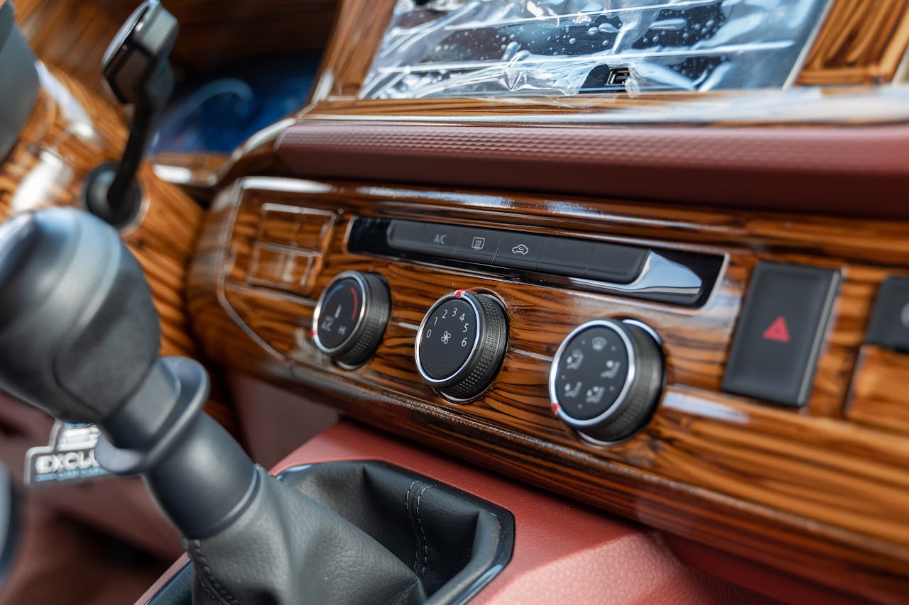 Close-up of a car dashboard with a woodgrain finish, manual gear shift in the foreground, glossy surface reflecting light, vintage or luxury vehicle interior