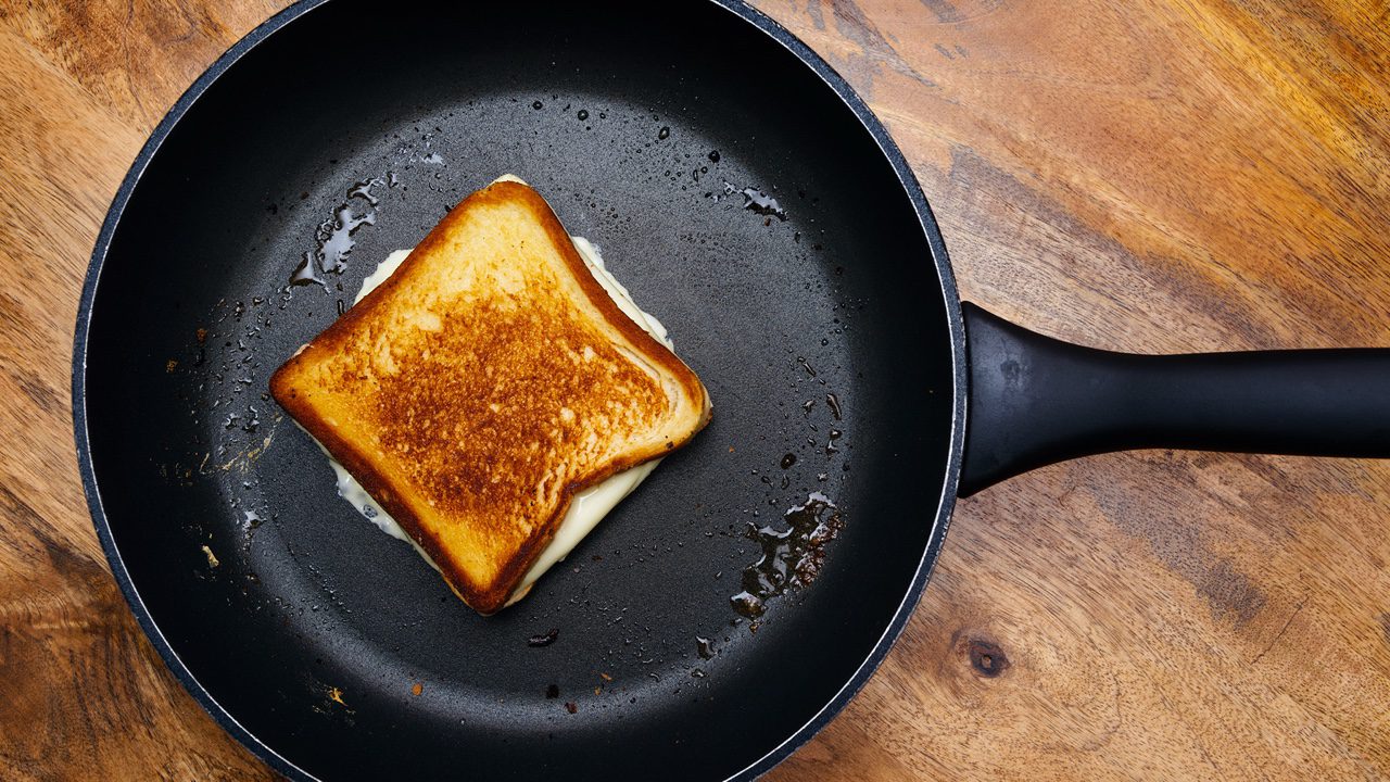Photo of a grilled cheese sandwich cooking in a large frying pan.
