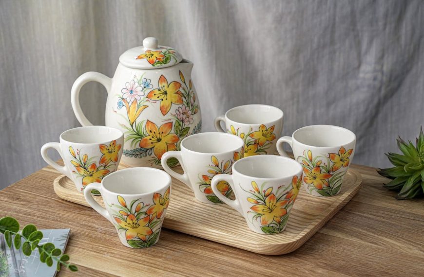 Floral tea set with teapot and six matching cups, yellow flower design, placed on wooden tray, light background