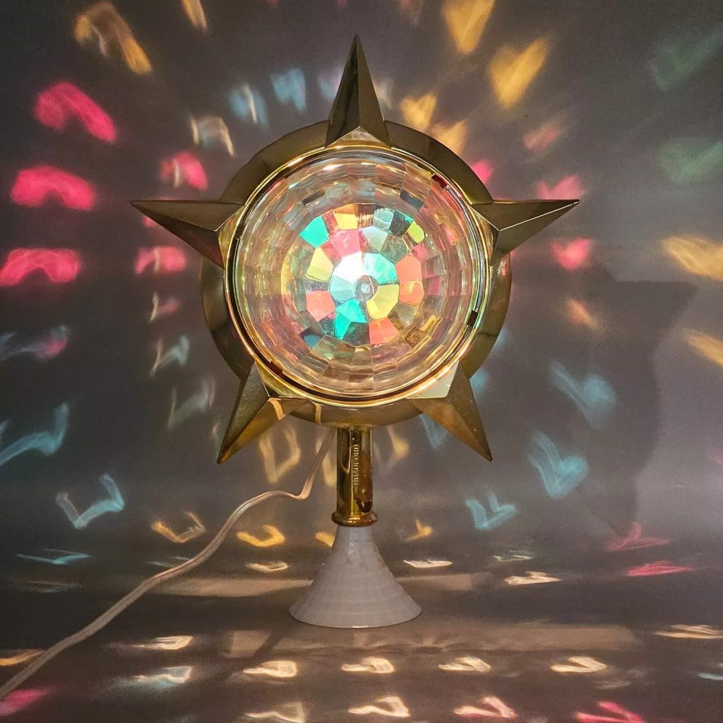 Vintage star shaped rotating color wheel light projecting vibrant multicolored reflections on the wall, with a retro base and electric cord visible