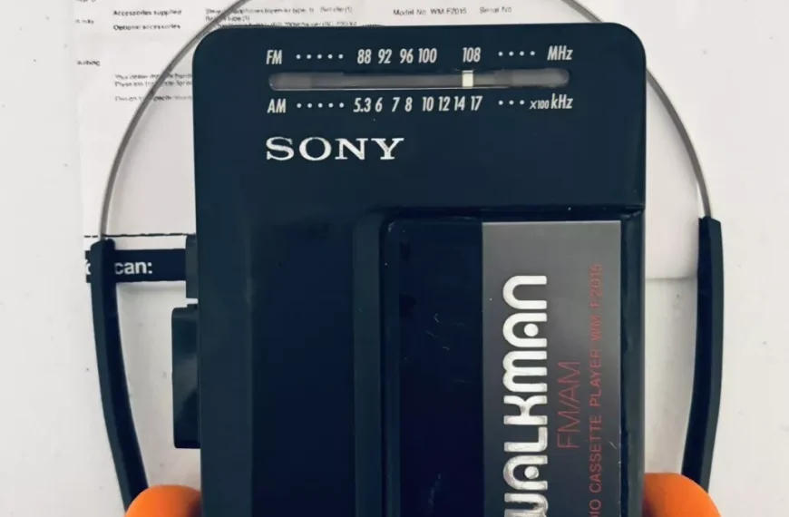Sony Walkman cassette player, black design with silver lettering, paired with retro orange foam headphones, classic portable music device, vintage audio technology