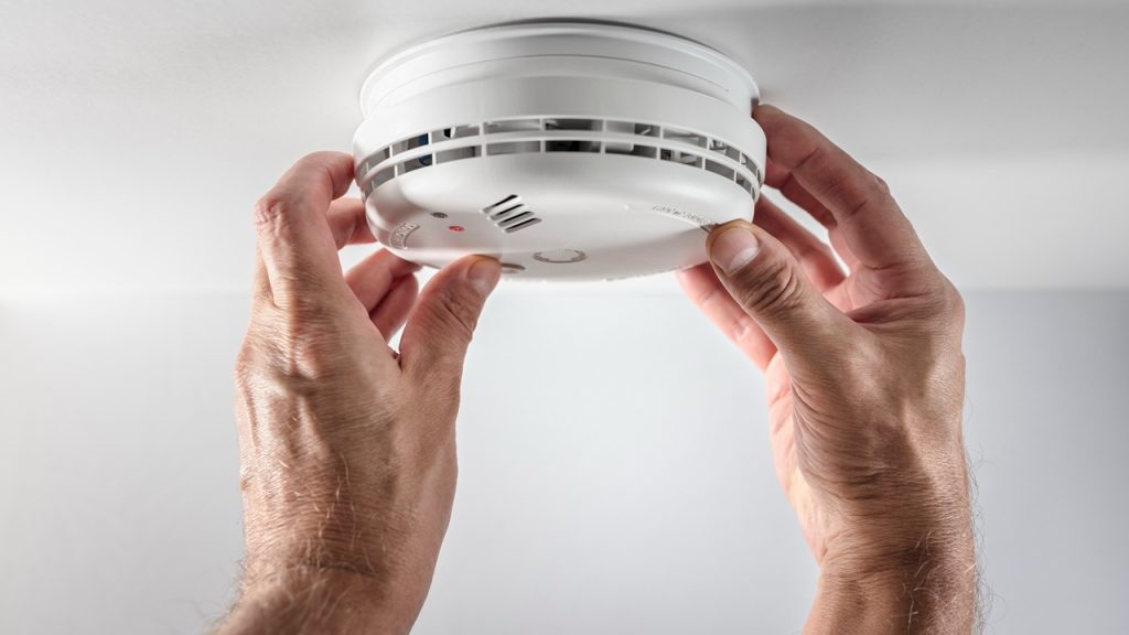 Home smoke and fire alarm detector man installing, maintenance, checking, testing or replacing battery
