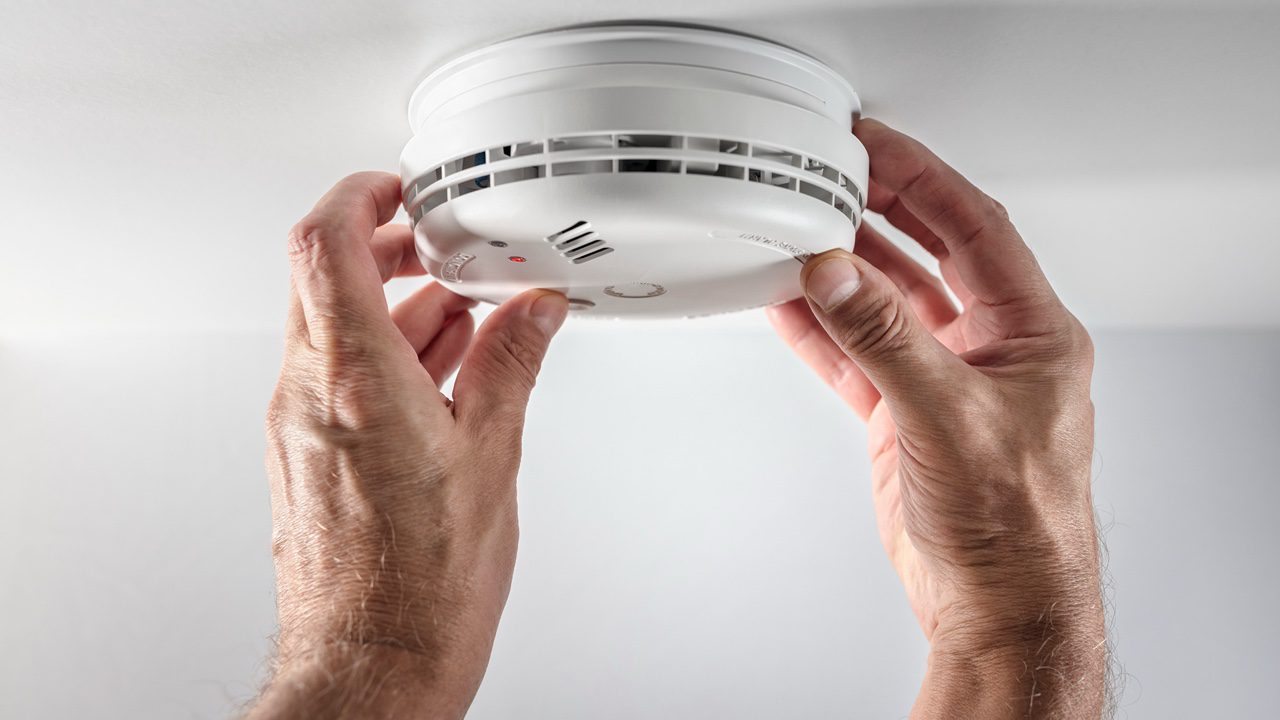 Home smoke and fire alarm detector man installing, maintenance, checking, testing or replacing battery