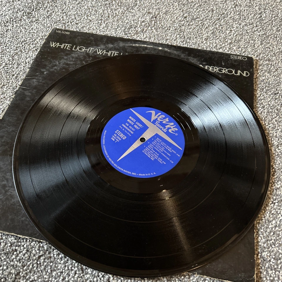 Vinyl record on its sleeve, black LP with a blue center label, classic album on a textured surface, vintage music collectible