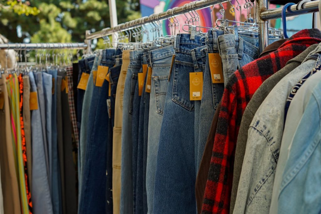 Assorted denim jeans on hangers, orange tags, outdoor clothing rack, flannel shirts, casual wear display