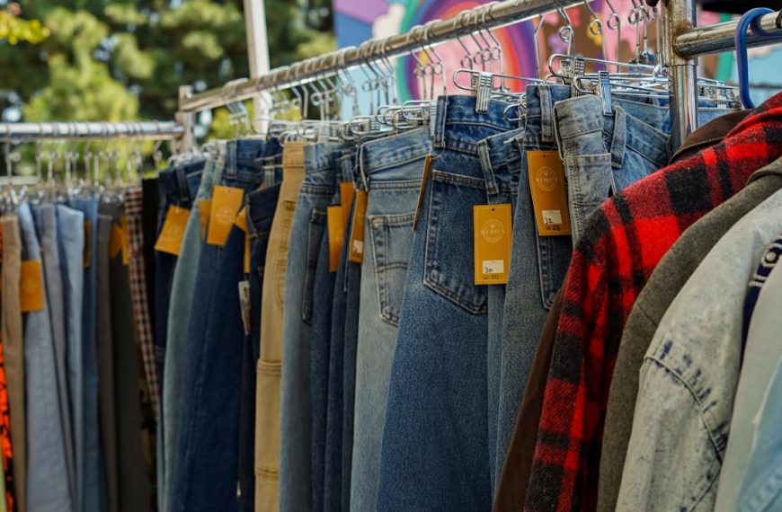 Assorted denim jeans on hangers, orange tags, outdoor clothing rack, flannel shirts, casual wear display