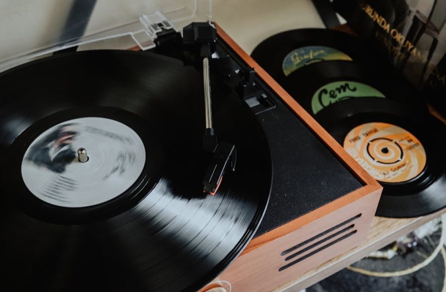 Close-up of a vintage record player, spinning a black vinyl, stacked records nearby, wooden casing, retro setup