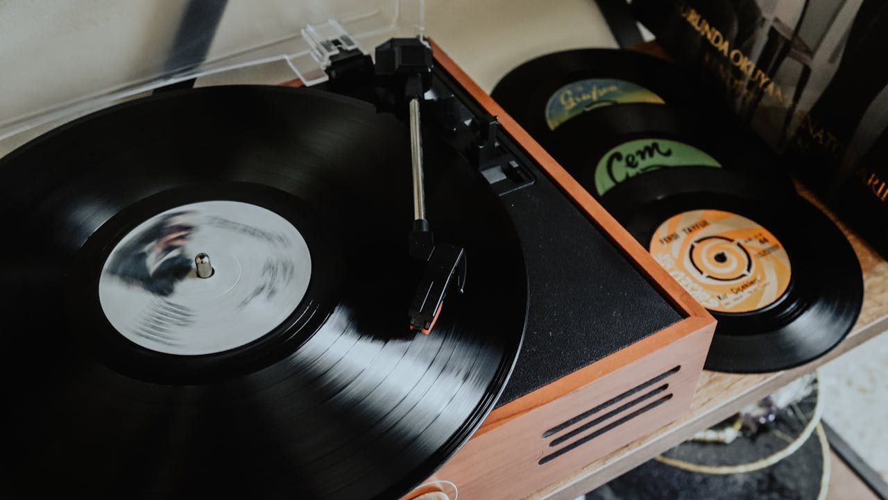 Close-up of a vintage record player, spinning a black vinyl, stacked records nearby, wooden casing, retro setup