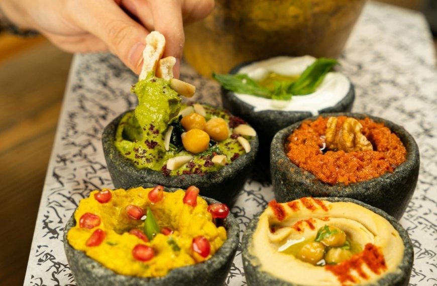 bowls of hummus surrounded by colorful veggie sticks