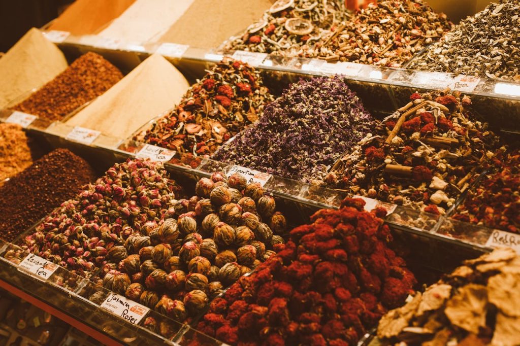 Colorful display of bulk spices and dried herbs in market bins, labeled sections with vibrant textures and natural ingredients
