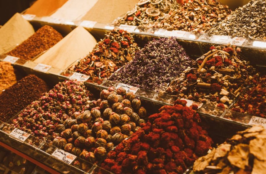 Colorful display of bulk spices and dried herbs in market bins, labeled sections with vibrant textures and natural ingredients