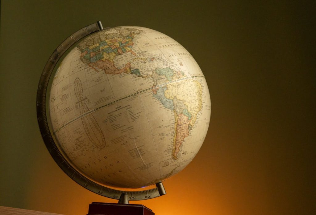 Vintage globe on a wooden base, tilted angle, displaying North and South America, warm lighting, dark green background