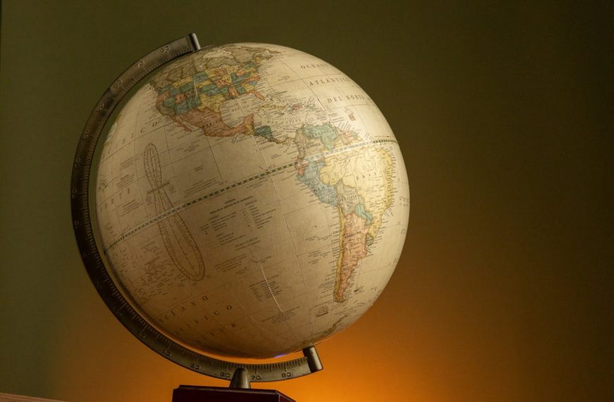 Vintage globe on a wooden base, tilted angle, displaying North and South America, warm lighting, dark green background