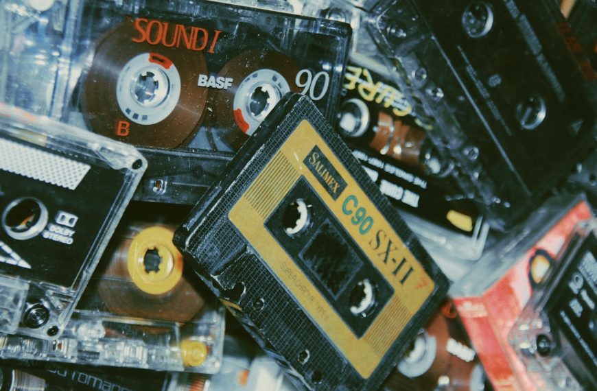 pile of assorted vintage cassette tapes, visible labels and brands, worn plastic shells, stacked in random arrangement