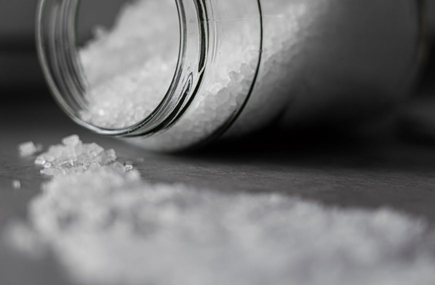 Spilled glass jar, fine white powder scattered on a surface, close-up, black and white image, soft focus on foreground
