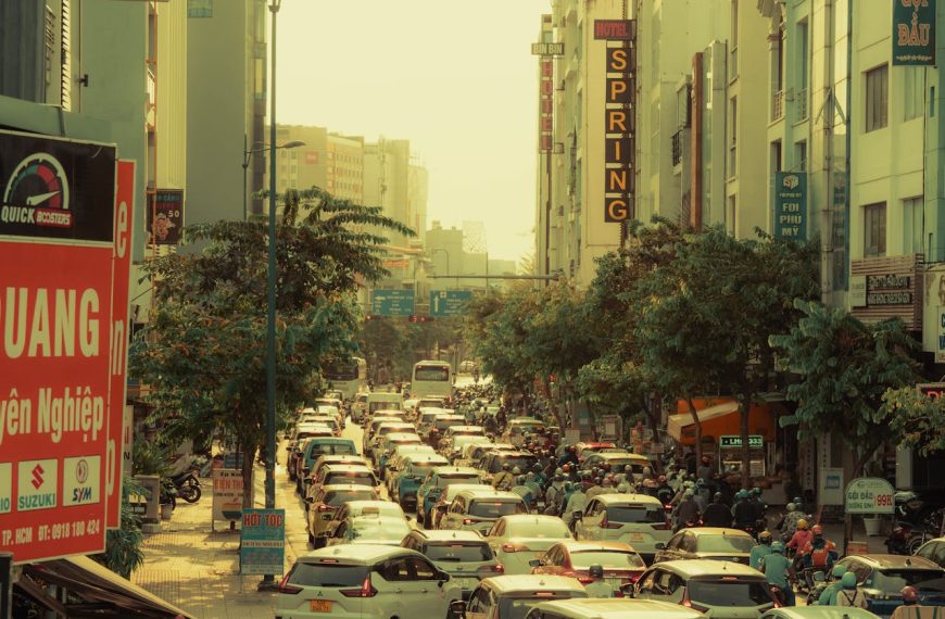 Congested Vietnamese street scene with heavy traffic, tall apartment buildings, Hotel Spring sign, and golden afternoon haze