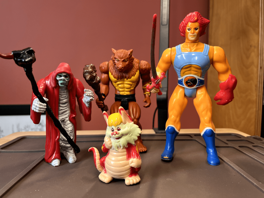 Collection of vintage action figures including ThunderCats characters and other 1980s toys displayed on shelf