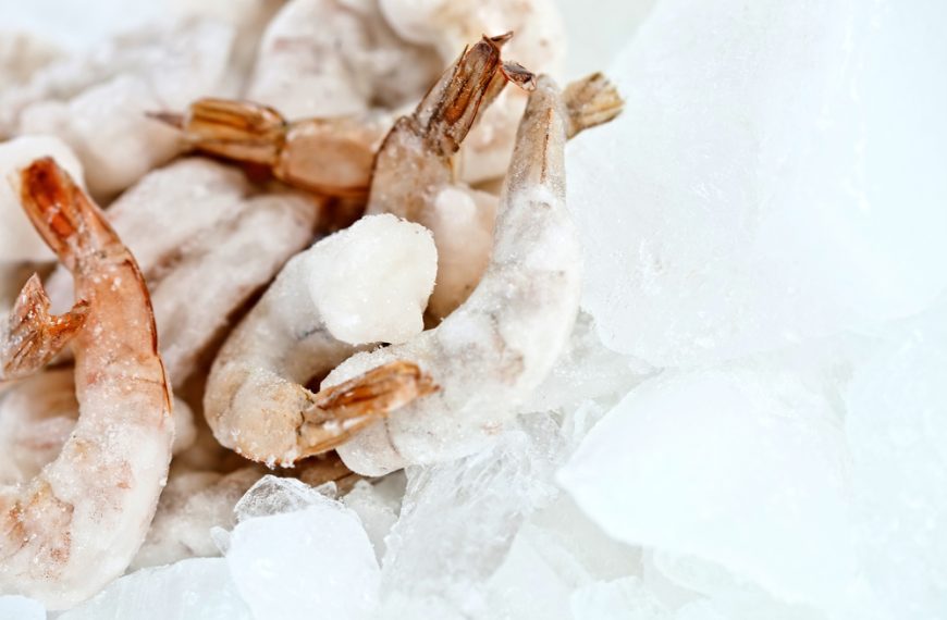 Frozen shrimp on a bed of ice, tails visible, close-up view