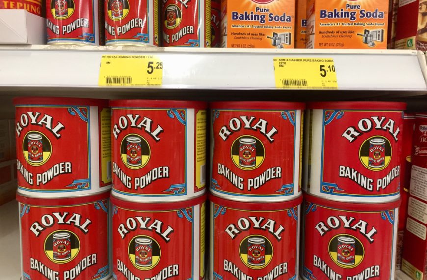 Royal Baking Powder and Arm & Hammer Baking Soda cans displayed on a supermarket shelf with price tags