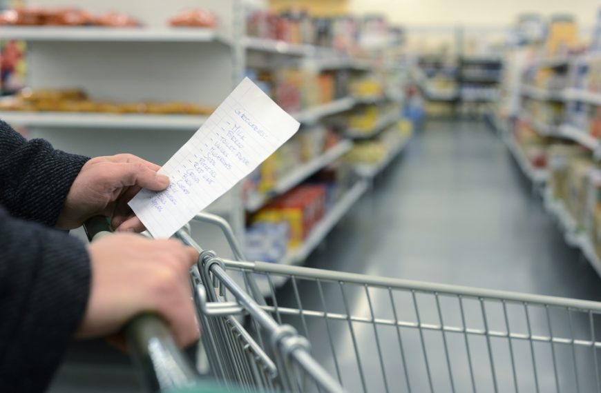 Hand holding a small spiral notepad with a handwritten list