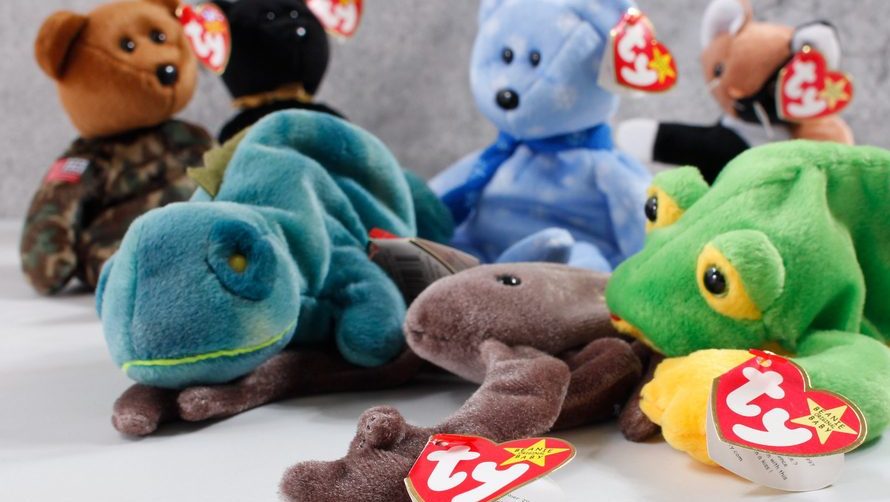 A group of TY Beanie Babies plush toys, including lizards, a bear, and other animals, arranged closely together