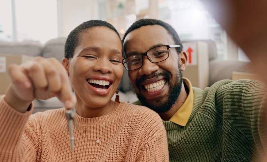 Happy couple smiling and holding keys, celebrating a new home or milestone.