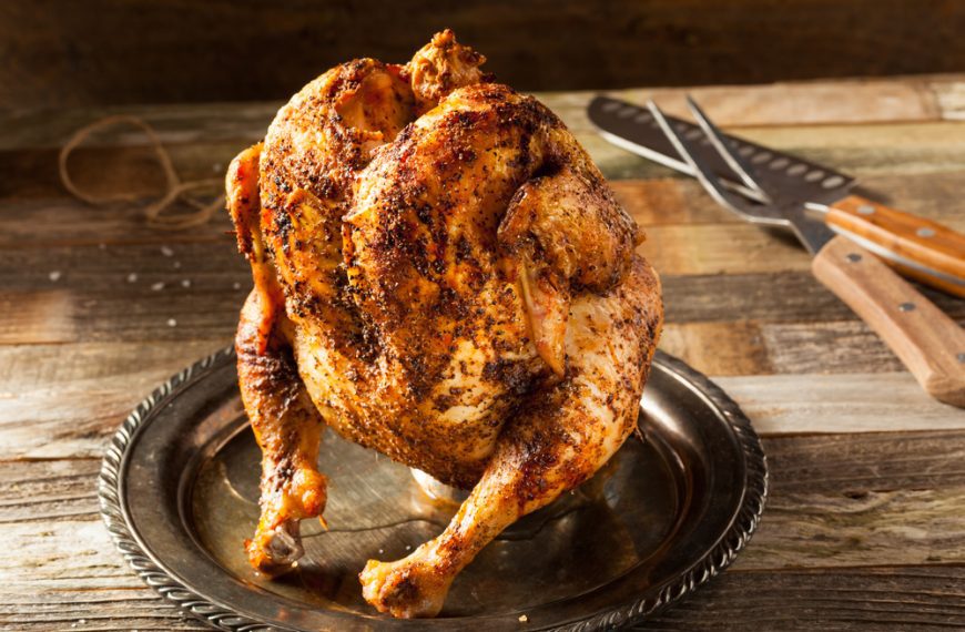 Whole roasted chicken, golden brown and crispy, served on a metal plate, seasoned with spices, home-cooked meal, holiday or family dinner