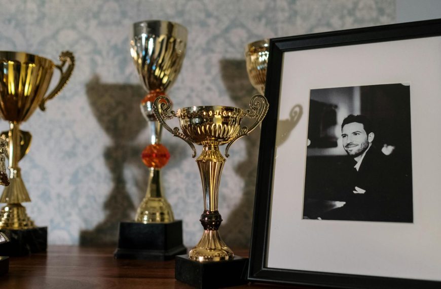 A collection of trophies with a framed black and white portrait on a shelf.