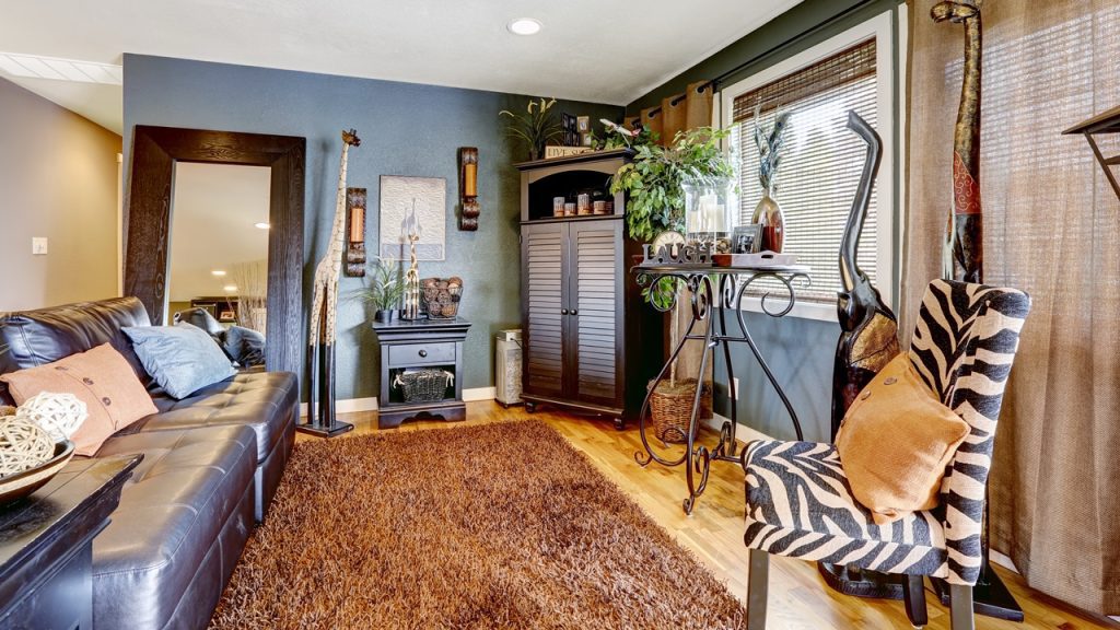 Animal decor, Cozy living room with a brown rug, blue accent wall, zebra-print chair, tall cabinet, indoor plants, and large windows
