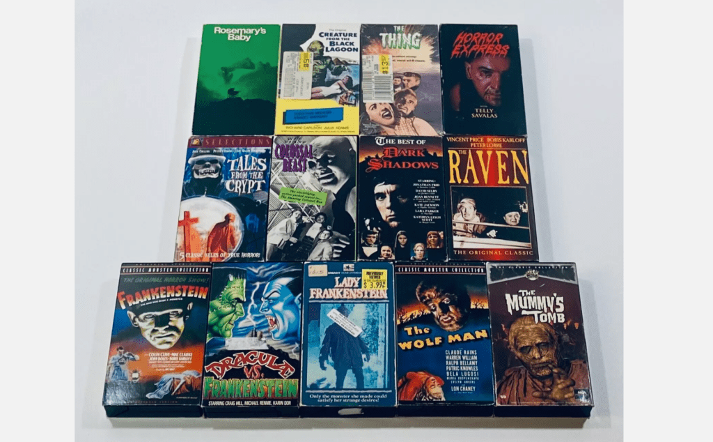 Collection of classic horror VHS tapes, titles include Rosemary’s Baby, The Thing, Frankenstein, The Wolf Man, The Mummy’s Tomb, displayed on white surface