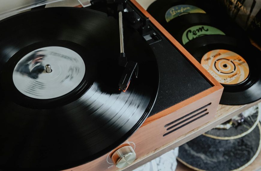 vintage record player spinning a black vinyl record, with stacked records visible nearby