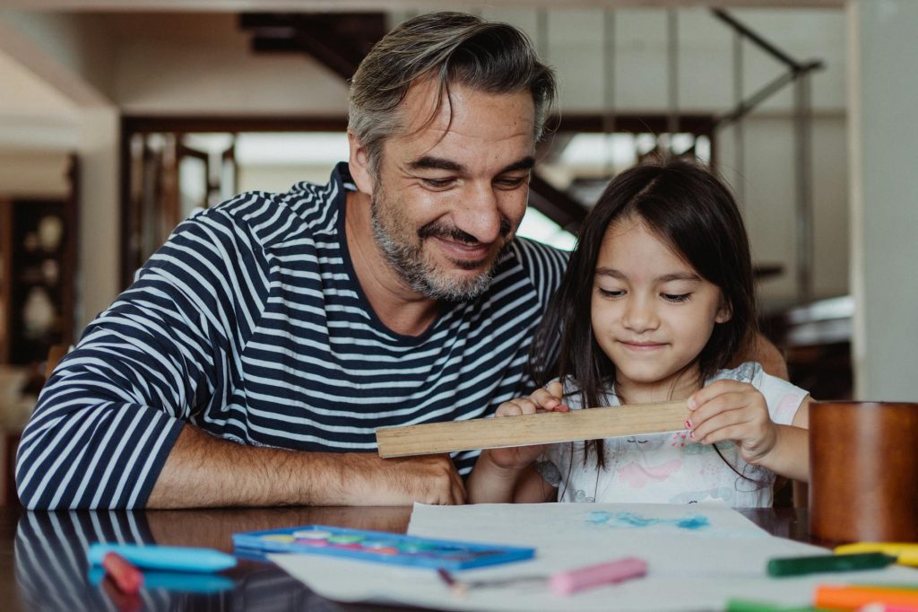 Father and daughter enjoying quality time painting and crafting indoors.