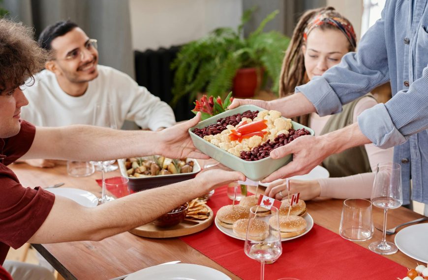 Joyful group of friends enjoying a meal together on Canada Day indoors.