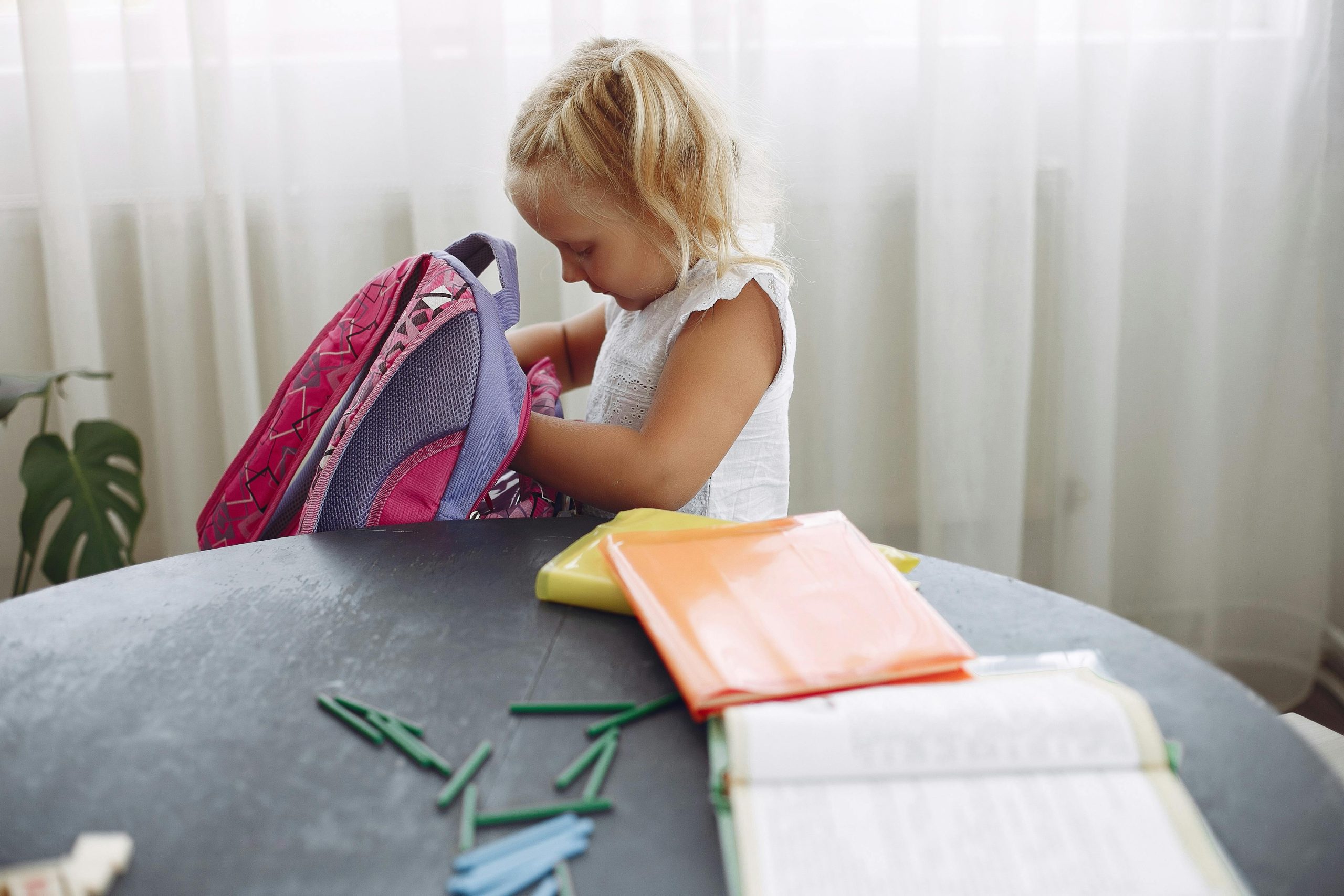 Concentrated girl searching pencil in backpack