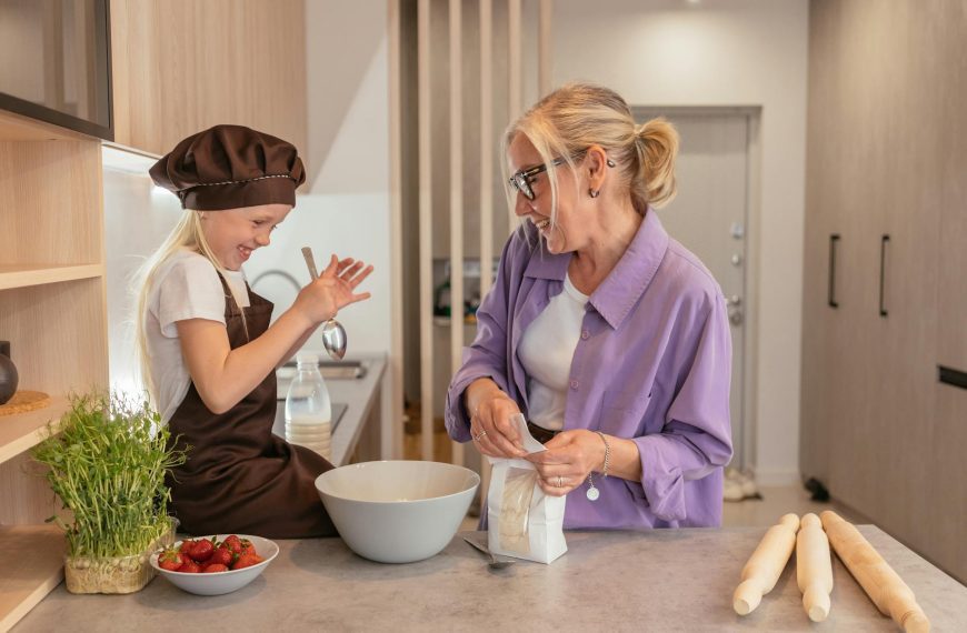 Cheerful grandma and granddaughter bonding while baking in the kitchen, sharing joyful moments.