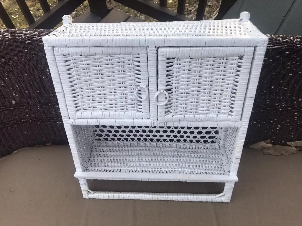White wicker cabinet, rectangular shape, two-door top compartment with circular handles, open lower shelf, woven design throughout