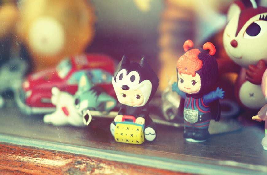 Assorted vintage plastic toys behind glass, including cartoon-style figures, a red toy car, and colorful character figurines