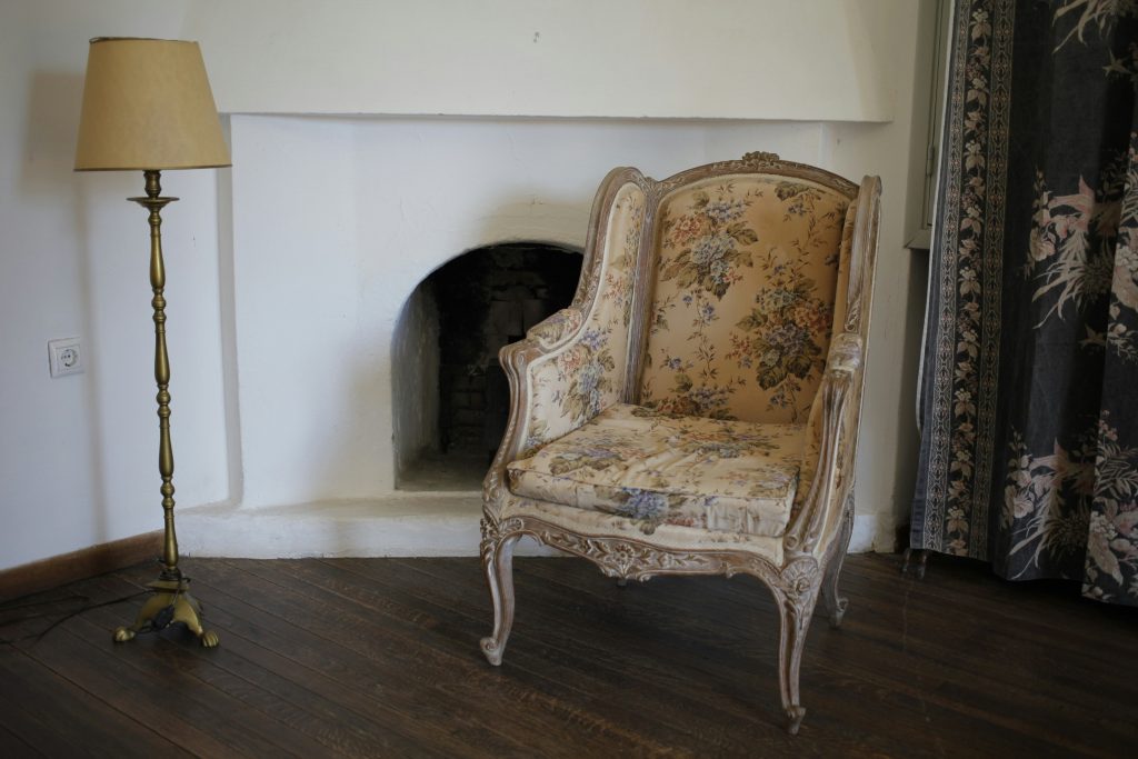 A victorian armchair in a room with a white free standing lamp