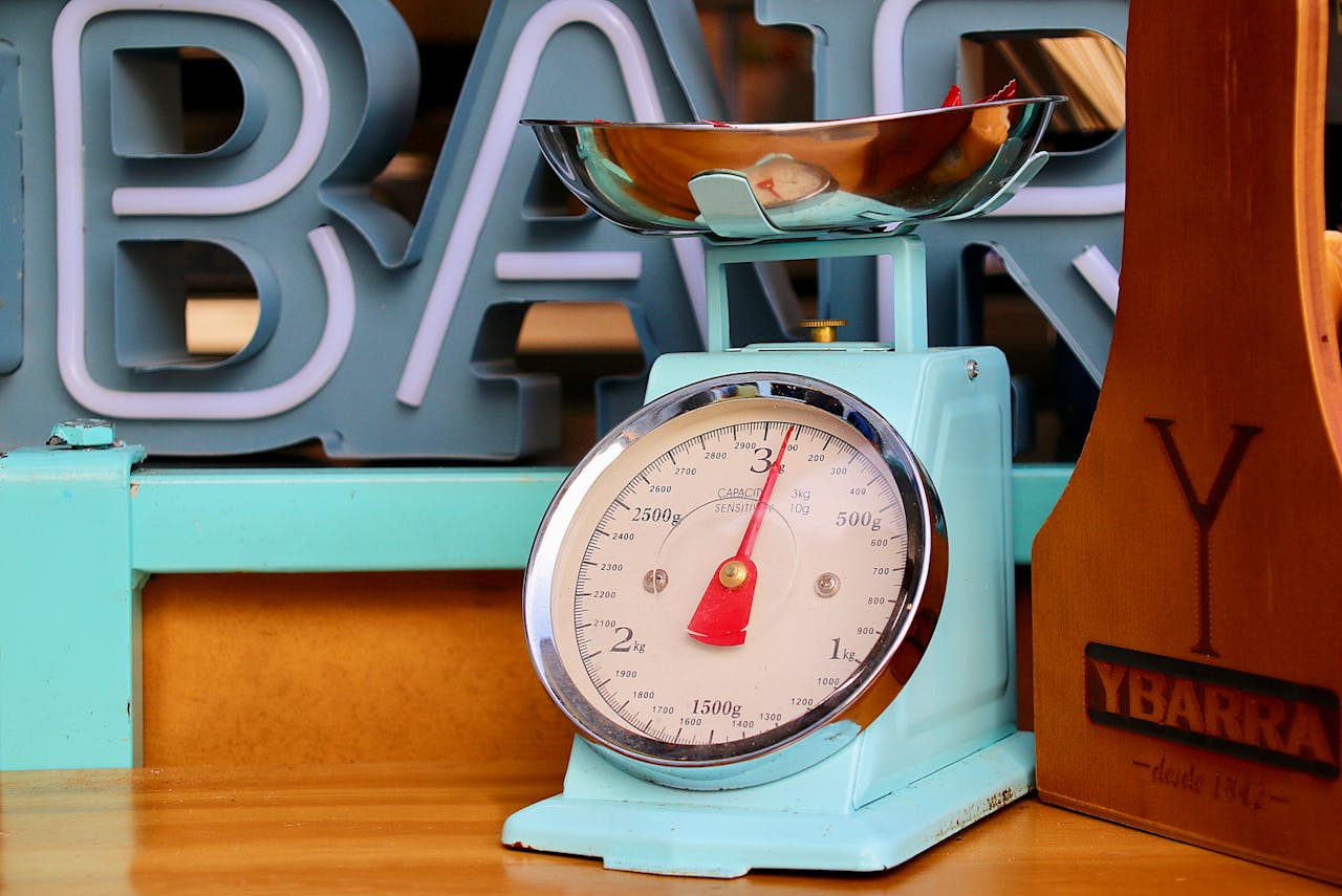 Light blue vintage kitchen scale with chrome bowl and red needle, set on wooden surface with background signage