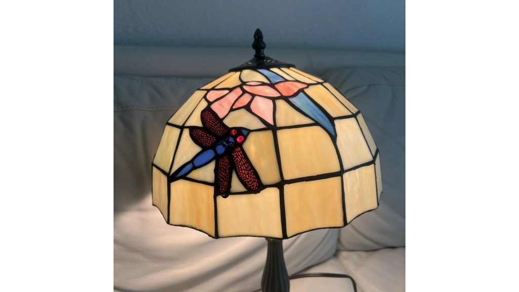 Stained glass table lamp, dome-shaped shade, dragonfly and floral design, warm yellow and pastel colors, black metal base