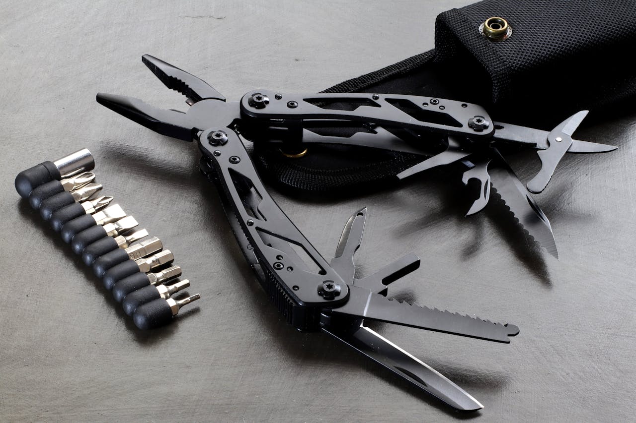 Black multitool with multiple extended components, including pliers, knife blades, saws, and screwdrivers