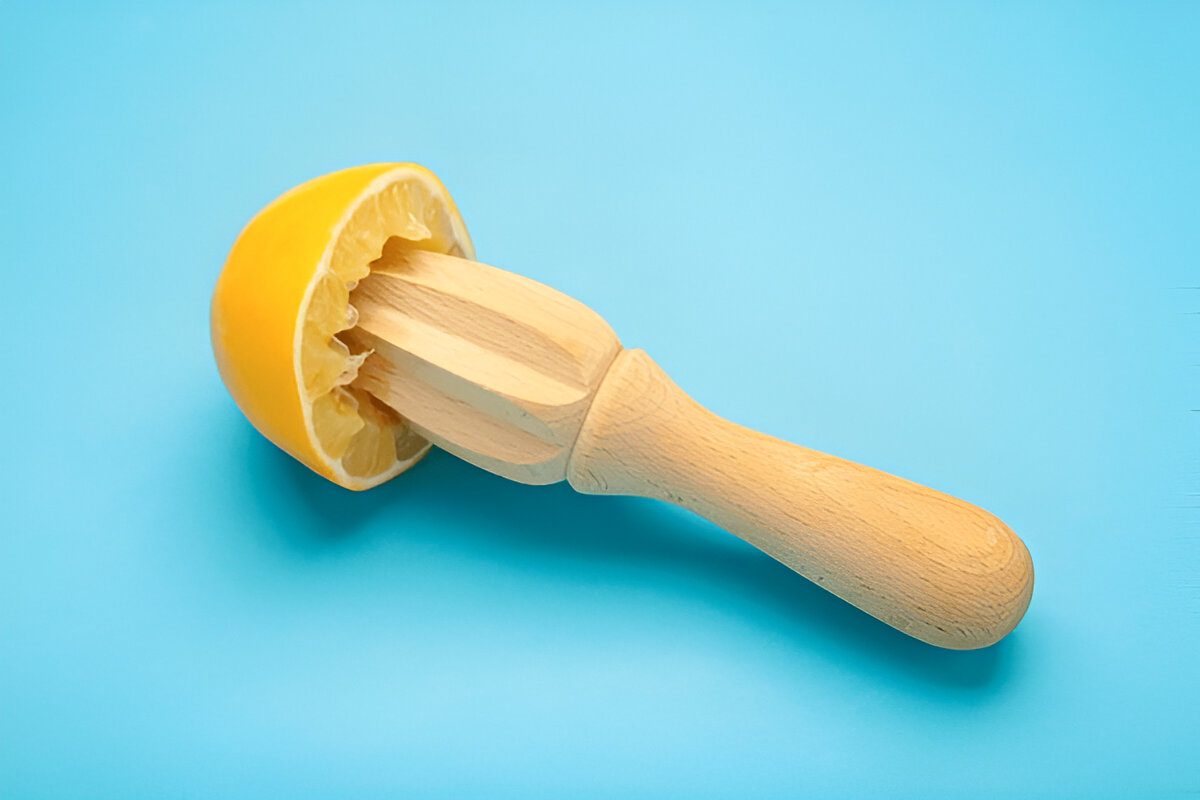 Wooden juicer with lemon on blue background. Top view