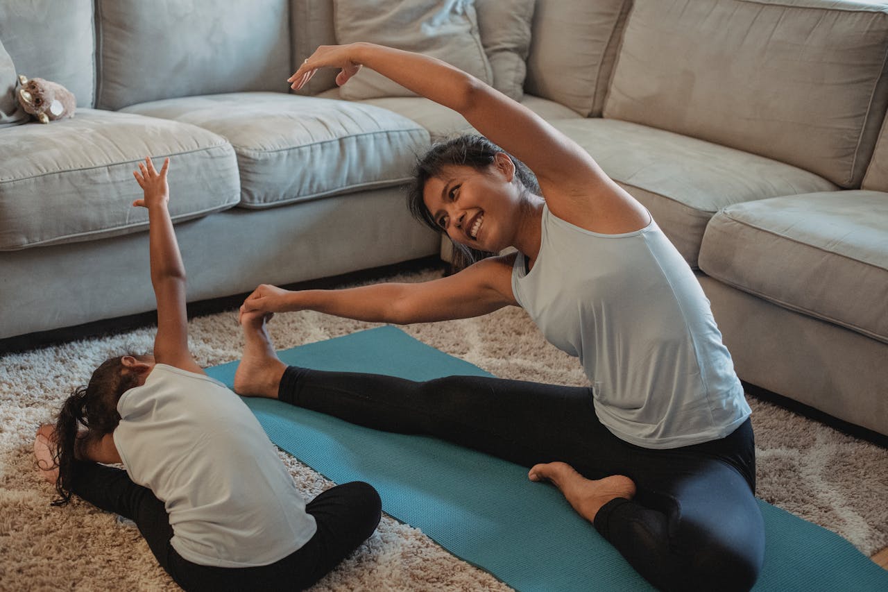Mother and daughter stretching together on a yoga mat in a living room